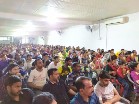 A diverse group of people in a professional meeting, looking at a presentation.